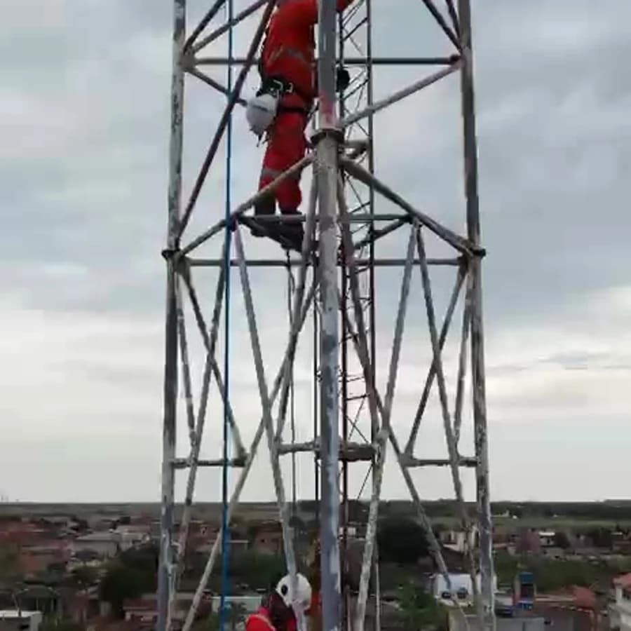 Técnicos em acesso por cordas realizando manutenção no topo da torre